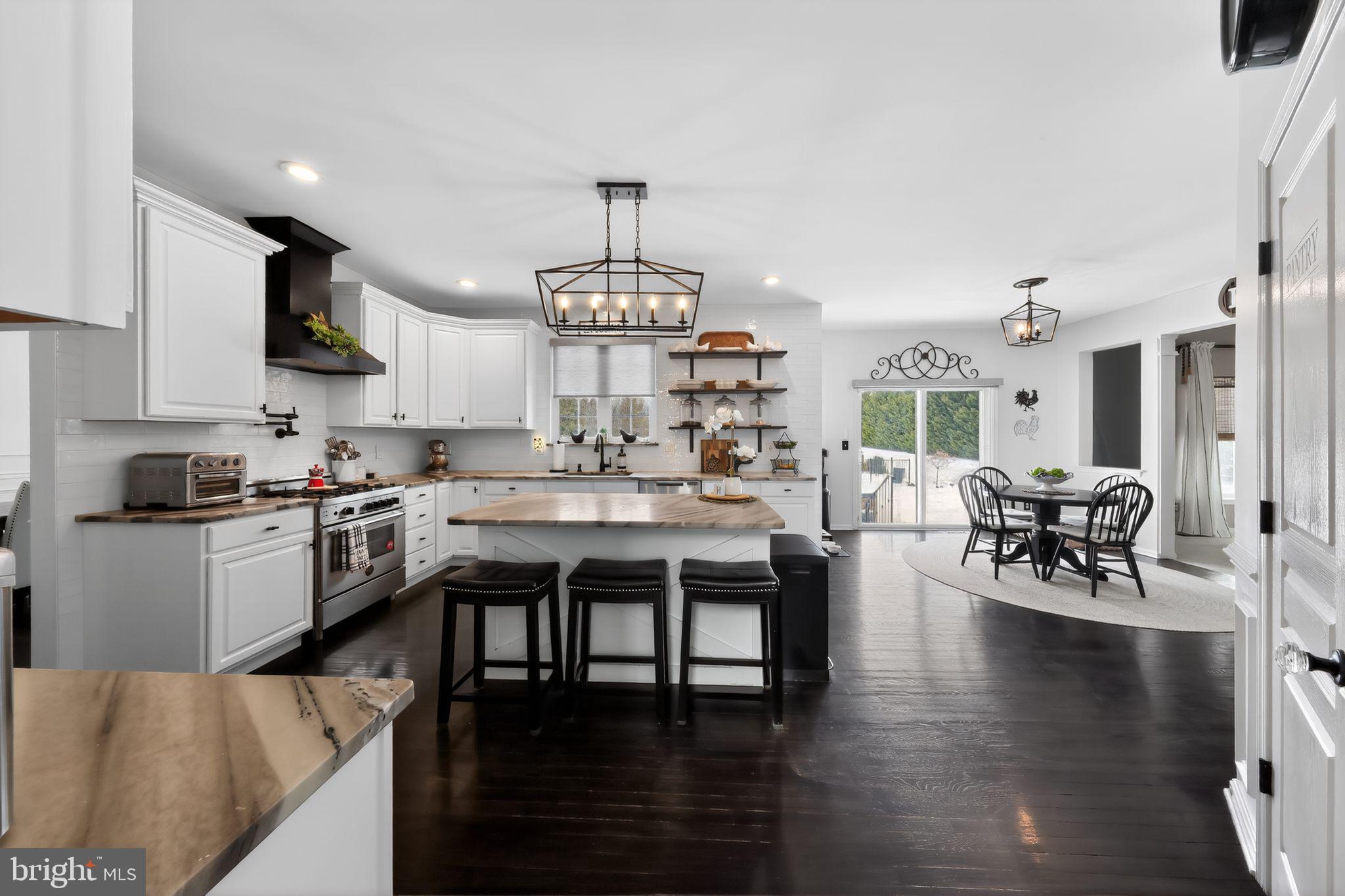 106 Coventry Lane Swedesboro, NJ 08085 - Photo 19 of 38 a kitchen with stainless steel appliances granite countertop a stove top oven a sink a dining table and chairs with wooden floor