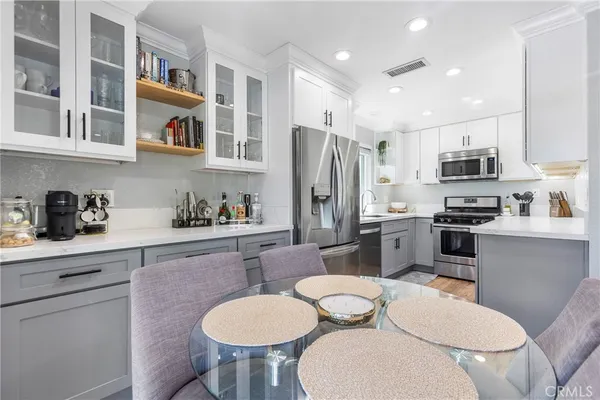 a kitchen with stainless steel appliances a sink a stove a refrigerator cabinets and dining table