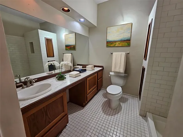a bathroom with a granite countertop toilet sink and mirror