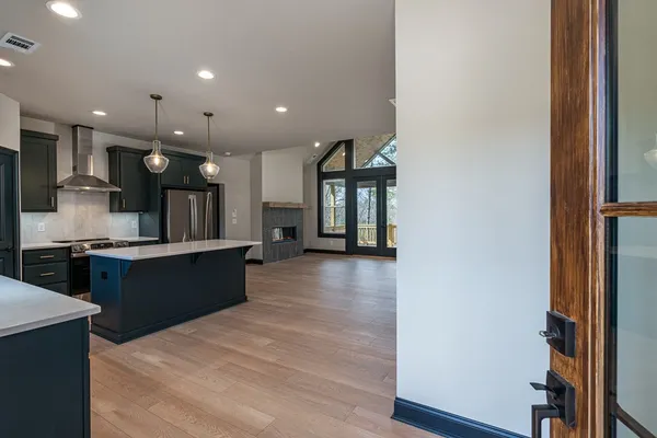 a large kitchen with stainless steel appliances kitchen island a large counter top and a wooden floor