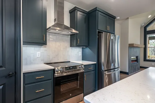 a kitchen with stainless steel appliances granite countertop a stove and a refrigerator with white cabinets