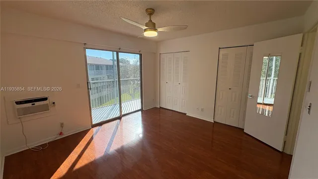 an empty room with wooden floor fan and windows