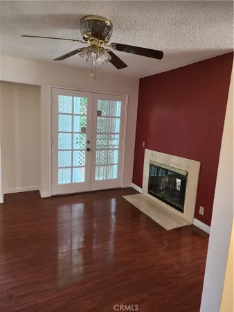 a view of an empty room with wooden floor fireplace and a window