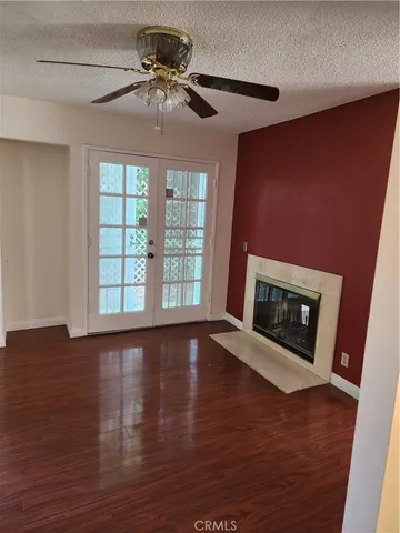 a view of an empty room with wooden floor fireplace and a window