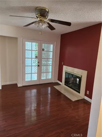 a view of an empty room with wooden floor fireplace and a window
