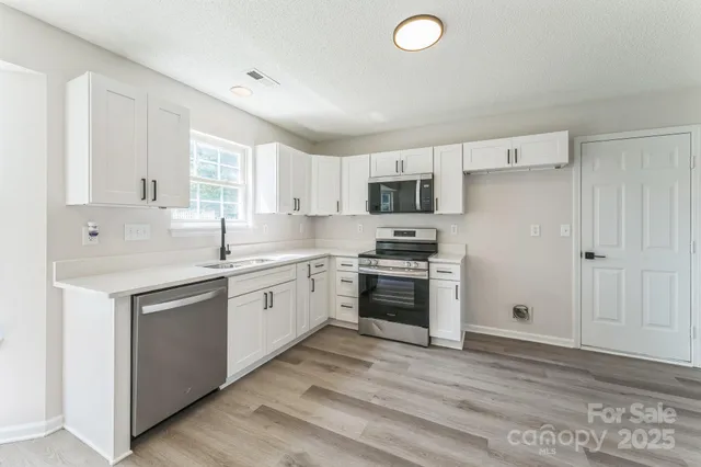 a kitchen with a sink cabinets stainless steel appliances and a window