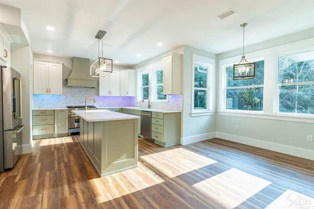 a large kitchen with kitchen island a large window a sink and stainless steel appliances