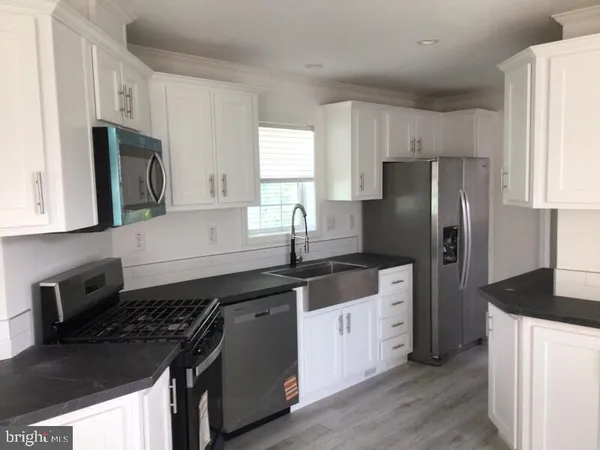 a kitchen with granite countertop a refrigerator stove and sink