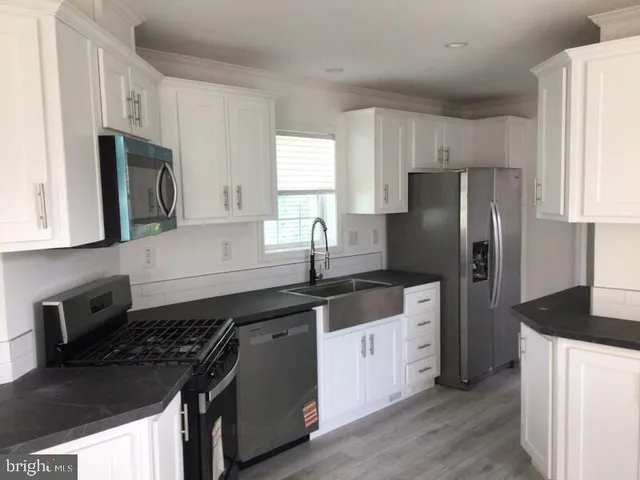 a kitchen with granite countertop a refrigerator stove and sink