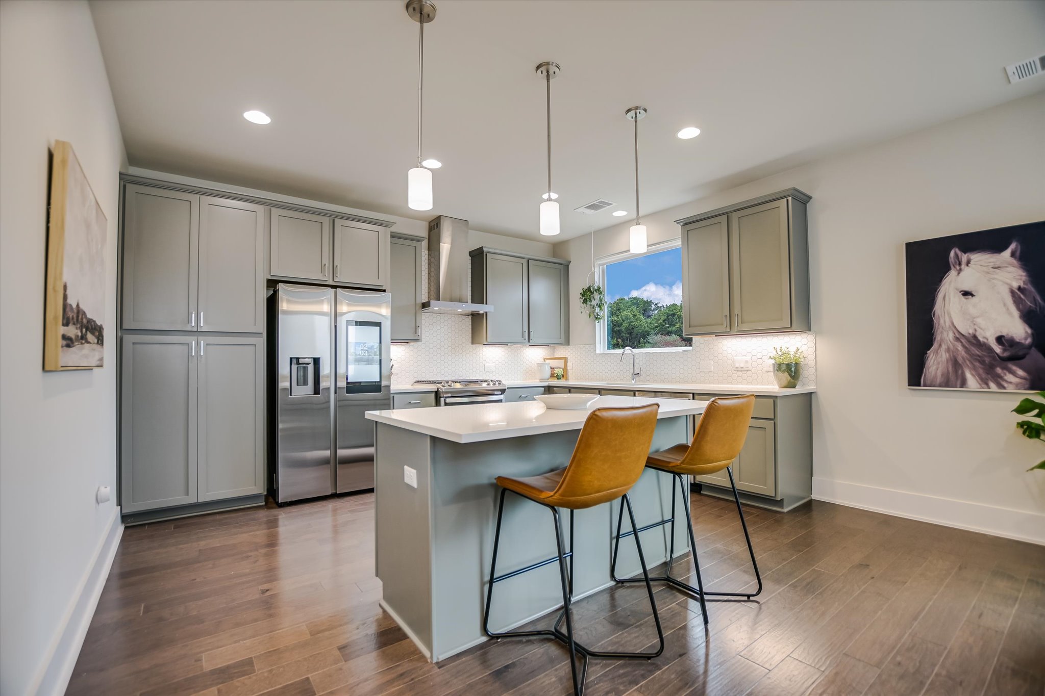 5212 Pink Poppy Pass, Unit 20 Austin, TX 78735 - Photo 8 of 24 Kitchen with gray cabinets, appliances with stainless steel finishes, decorative light fixtures, a kitchen breakfast bar, and a kitchen island