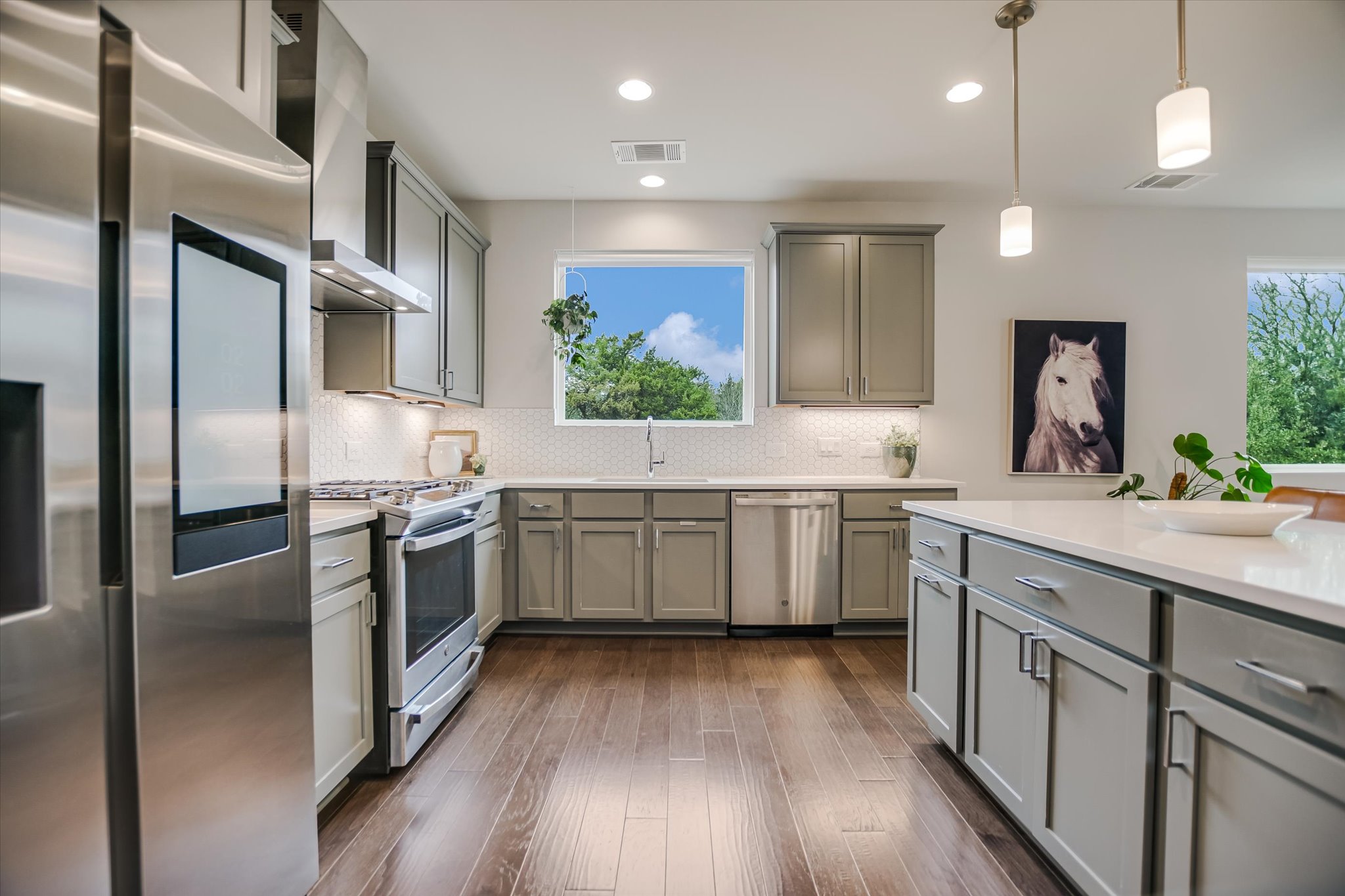 5212 Pink Poppy Pass, Unit 20 Austin, TX 78735 - Photo 9 of 24 Kitchen with appliances with stainless steel finishes, gray cabinets, wall chimney range hood, pendant lighting, and recessed lighting