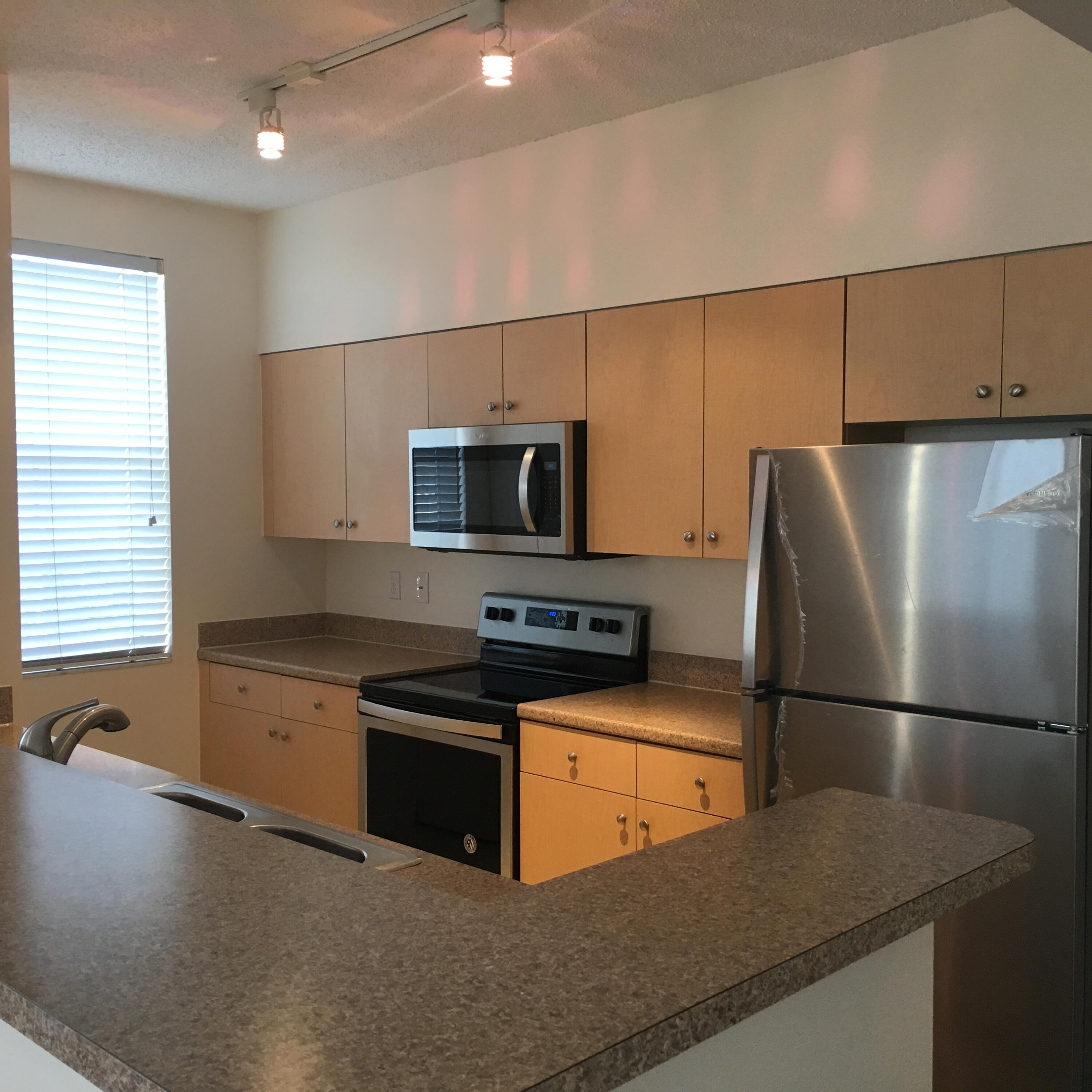 616 Clearwater Park Road, Unit 413 West Palm Beach, FL 33401 - Photo 6 of 21 a kitchen with granite countertop a refrigerator a sink a stove a microwave and island