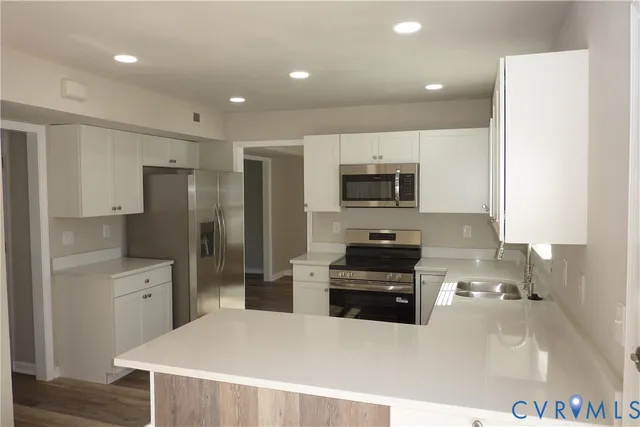 a kitchen with stainless steel appliances a stove a sink a microwave a refrigerator and cabinets