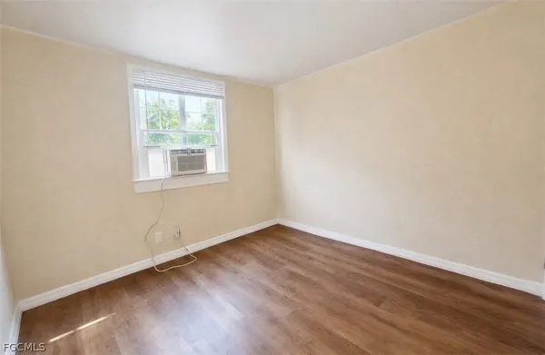 an empty room with wooden floor and window