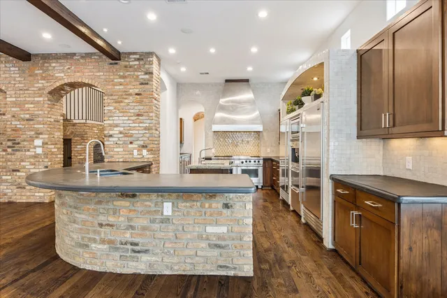 a large kitchen with granite countertop a large counter top space a sink stainless steel appliances and cabinets