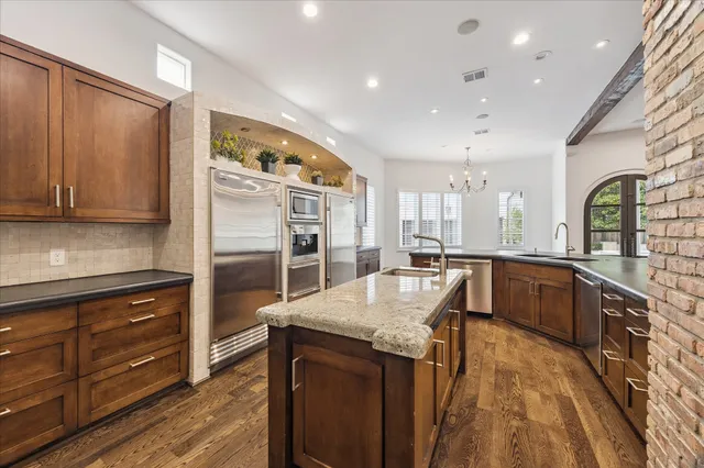 a large kitchen with granite countertop a large counter top stainless steel appliances and cabinets
