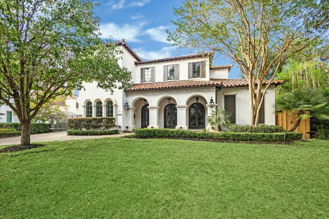 a white house with a big yard and large trees