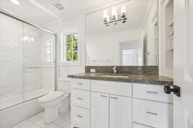 a bathroom with a granite countertop sink a toilet and shower