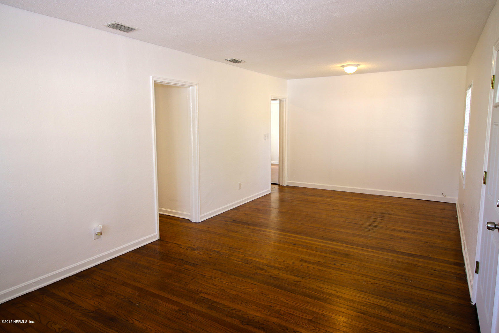 4934 Dundee Road Jacksonville, FL 32210 - Photo 4 of 15 an empty room with wooden floor and windows