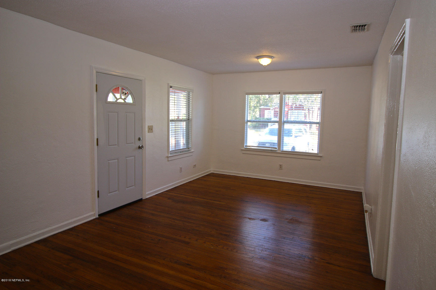 4934 Dundee Road Jacksonville, FL 32210 - Photo 5 of 15 an empty room with wooden floor and windows