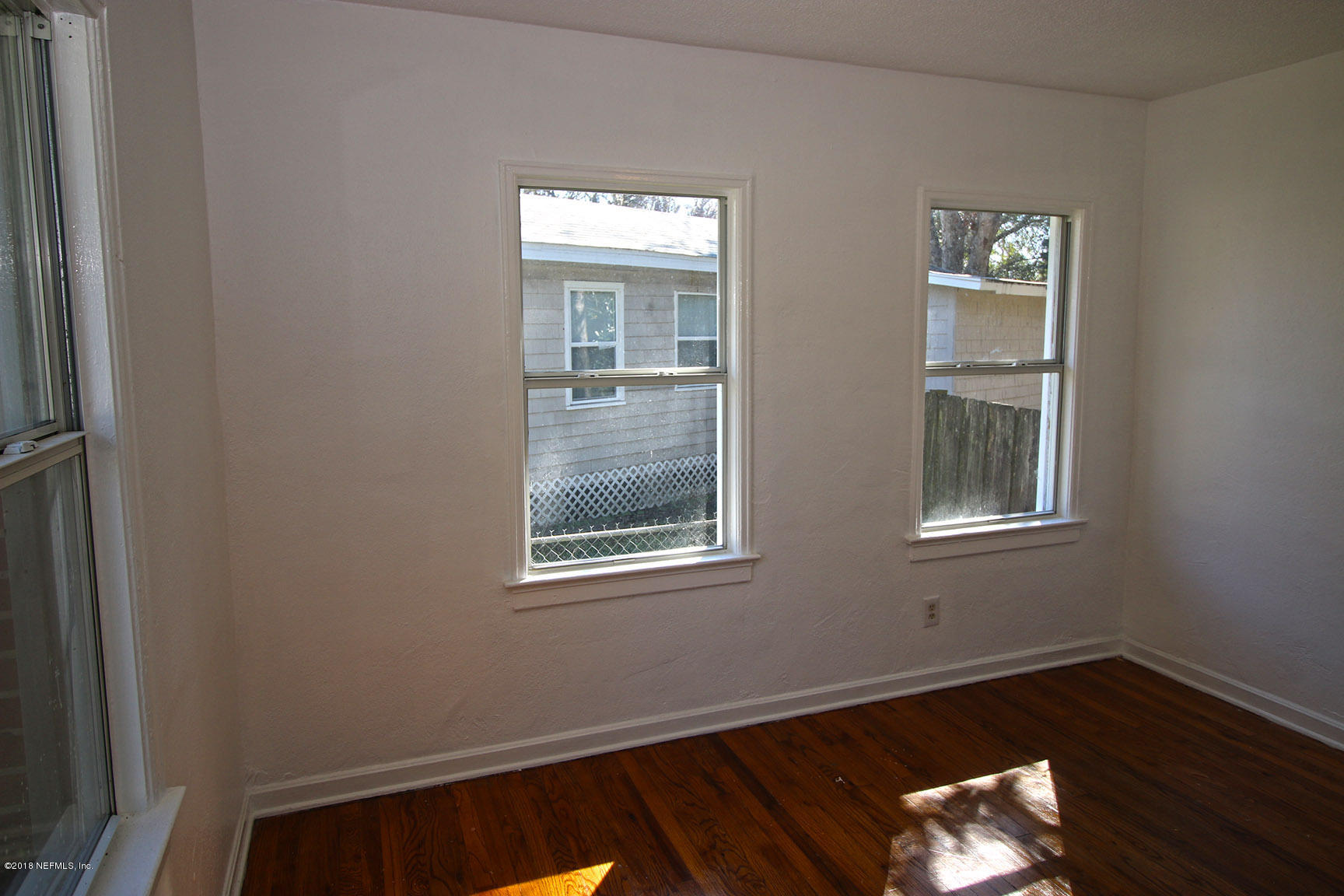 4934 Dundee Road Jacksonville, FL 32210 - Photo 9 of 15 a view of an empty room with wooden floor and a window