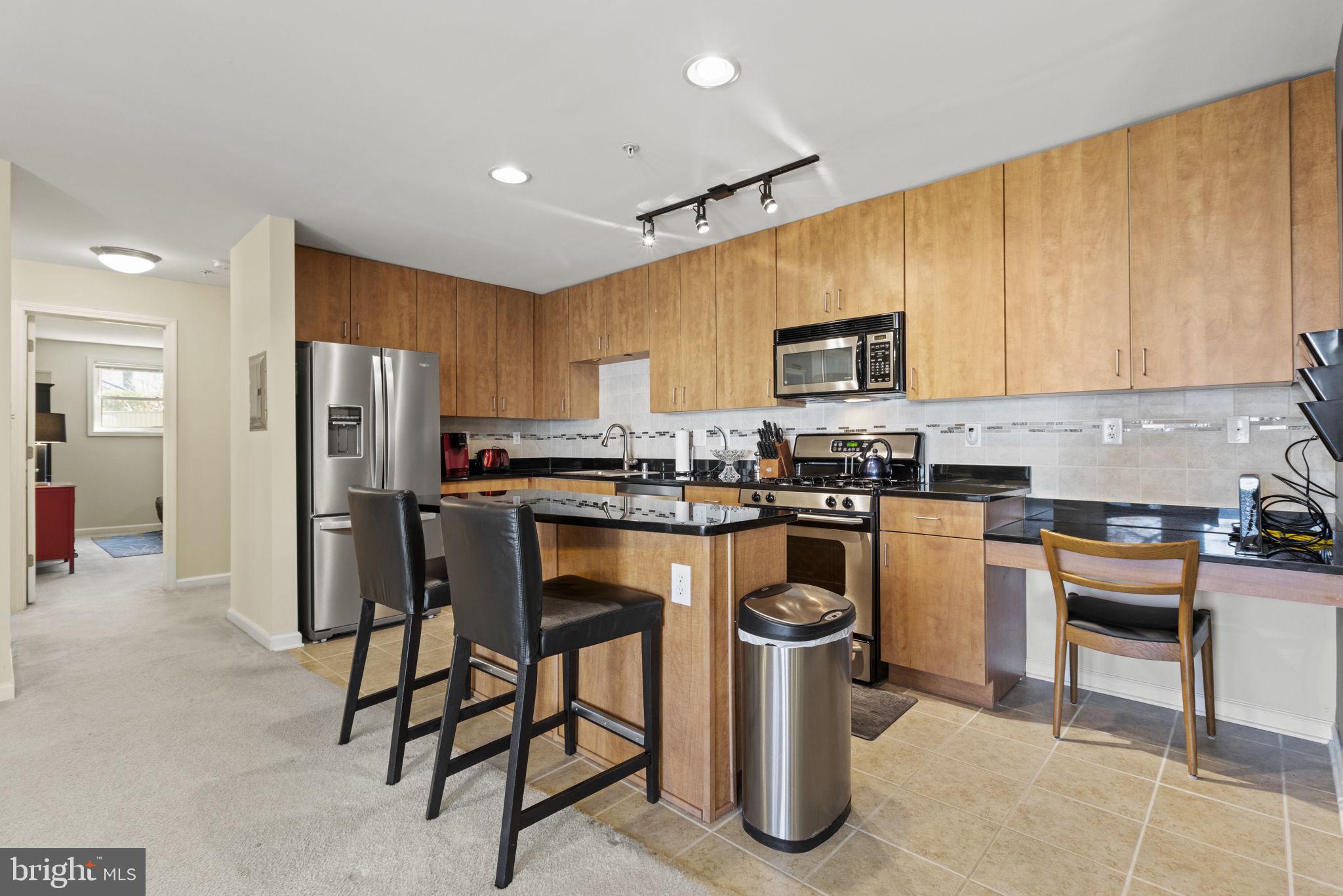a kitchen with stainless steel appliances granite countertop a stove a sink a refrigerator and a microwave