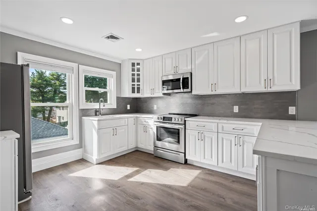 a kitchen with stainless steel appliances granite countertop a stove a sink and white cabinets