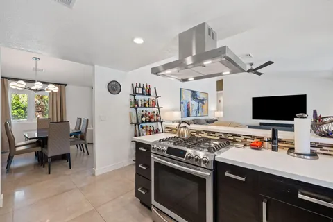 a kitchen with a stove a sink and a dining table with white walls