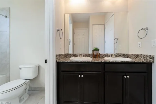 a bathroom with a granite countertop sink a toilet and a mirror
