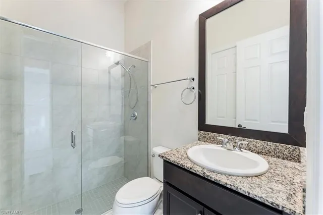 a bathroom with a granite countertop sink toilet a mirror a shower and a mirror