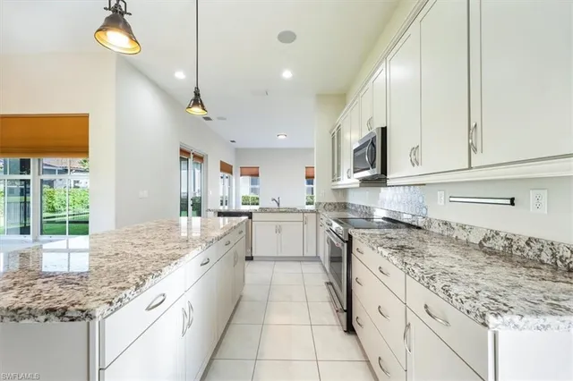 a large white kitchen with granite countertop a sink and dishwasher a stove top oven with wooden floor