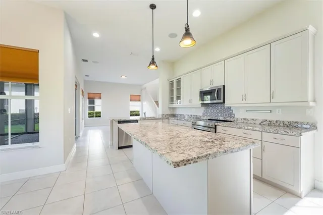 a kitchen with stainless steel appliances granite countertop a stove top oven a sink dishwasher a refrigerator and white cabinets with wooden floor