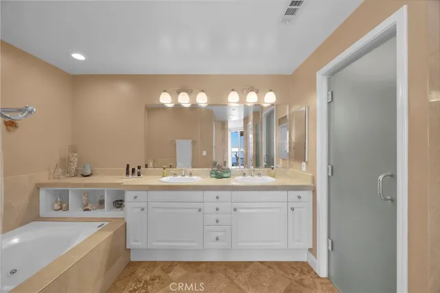 a bathroom with a sink a large mirror and a bathtub with double vanity