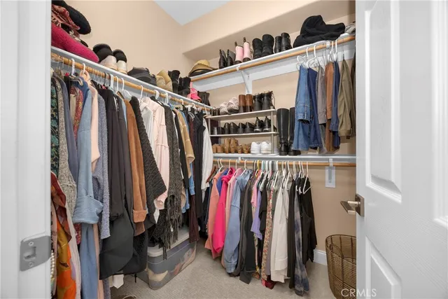 a view of walk in closet with clothes and shoes