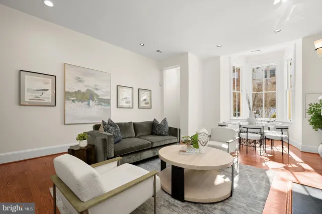 a living room with couches and a dining table with wooden floor