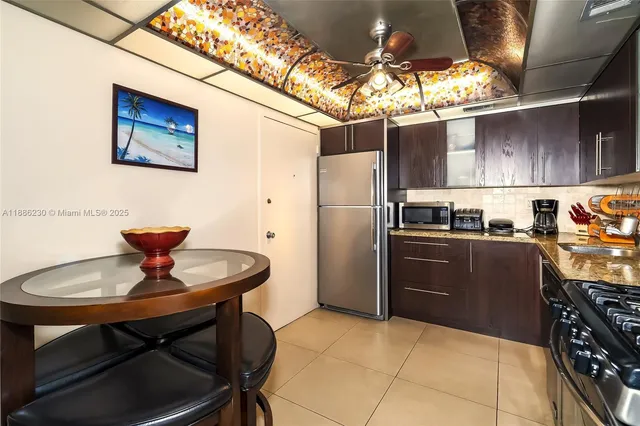 a kitchen with stainless steel appliances granite countertop a sink a stove a refrigerator cabinets and dining table