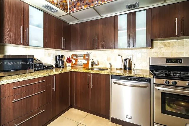 a kitchen with stainless steel appliances granite countertop a refrigerator and a stove top oven