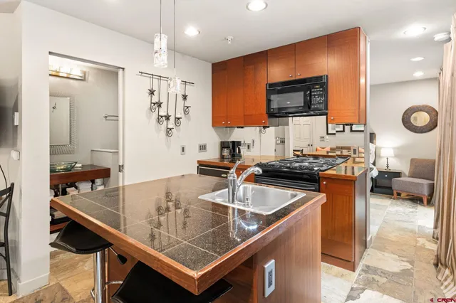 a kitchen with stainless steel appliances granite countertop a sink a stove counter space and cabinets