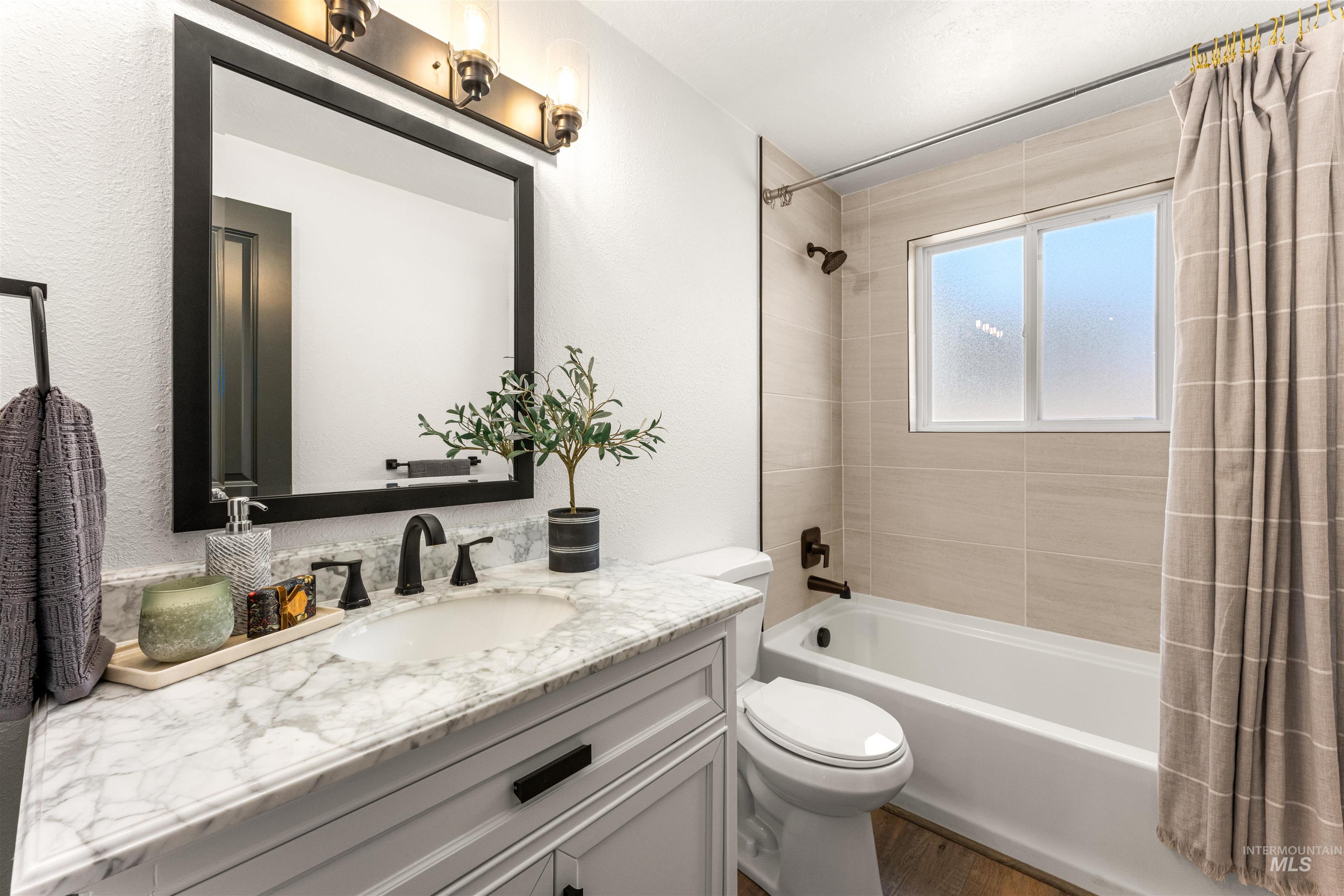 4700 Jennifer Street Boise, ID 83704 - Photo 26 of 39 Bathroom featuring a white vanity with a marble-finish countertop, a rectangular mirror, and a three-light fixture