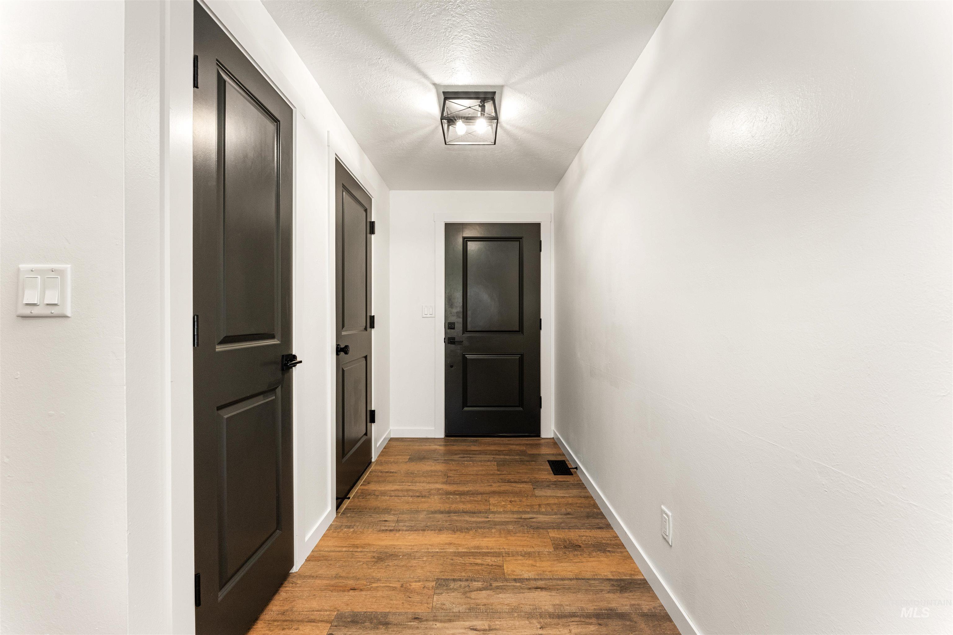 4700 Jennifer Street Boise, ID 83704 - Photo 7 of 39 Hallway featuring wood-finish flooring, crisp white walls, and dark panel doors with matte black hardware