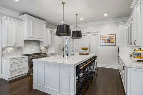 a kitchen with kitchen island stainless steel appliances a sink a stove and a wooden floors