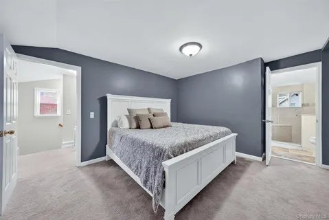 a spacious bedroom with a bed and painting on the wall