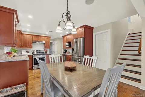 a view of a dining room and livingroom with furniture wooden floor kitchen view and a chandelier