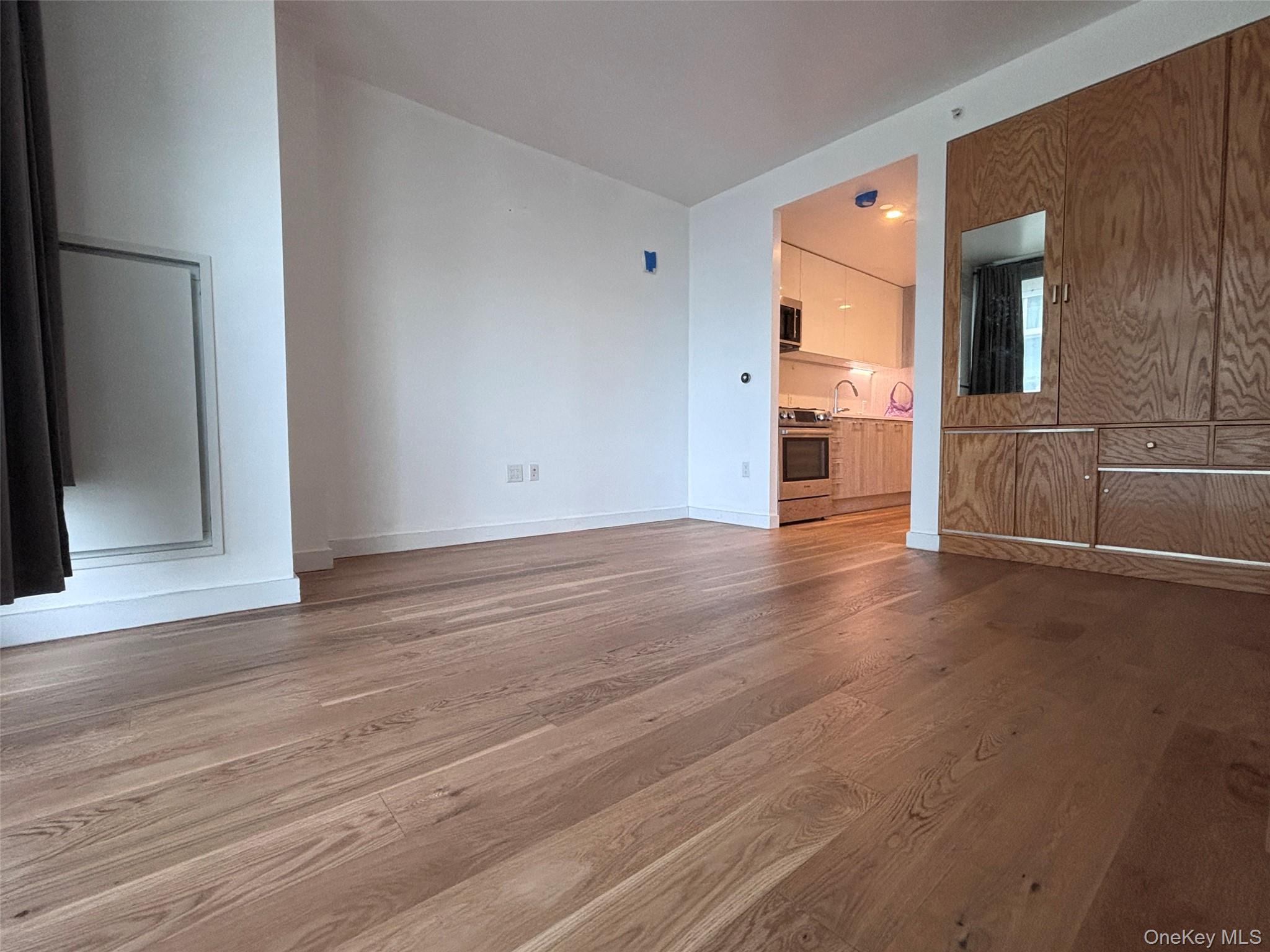 131-03 40 Road, Unit 15L Queens, NY 11354 - Photo 3 of 11 a view of a kitchen cabinets and wooden floor