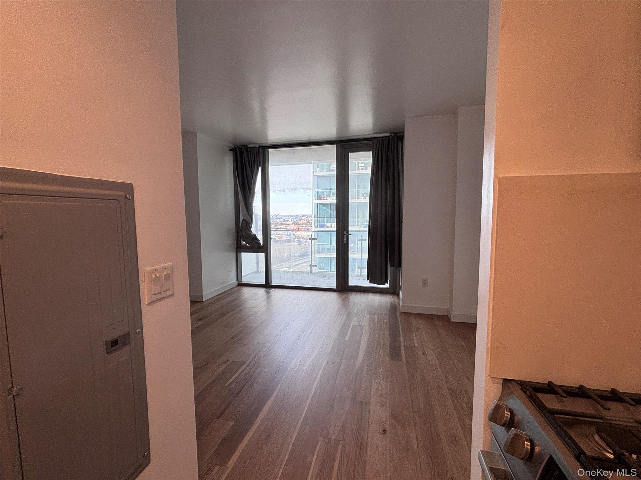 131-03 40 Road, Unit 15L Queens, NY 11354 - Photo 4 of 11 wooden floor in an empty room with a window
