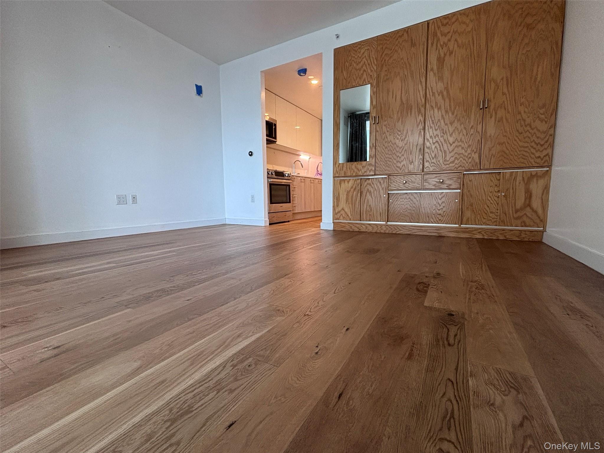 131-03 40 Road, Unit 15L Queens, NY 11354 - Photo 5 of 11 a view of a kitchen with wooden floor and electronic appliances