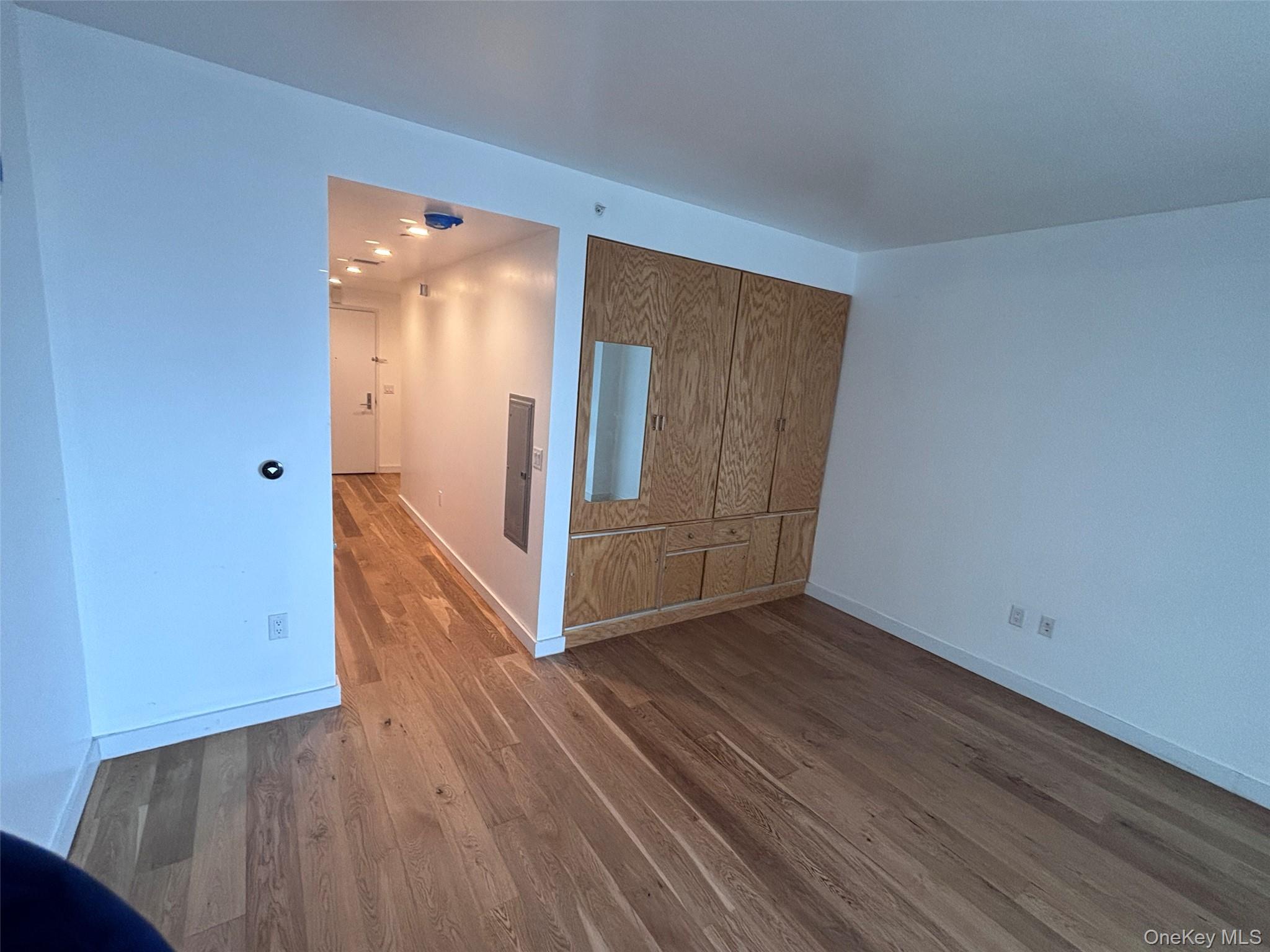131-03 40 Road, Unit 15L Queens, NY 11354 - Photo 7 of 11 an empty room with wooden floor and entrance