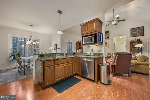 a kitchen with stainless steel appliances granite countertop a sink dishwasher a stove and a refrigerator with wooden floor