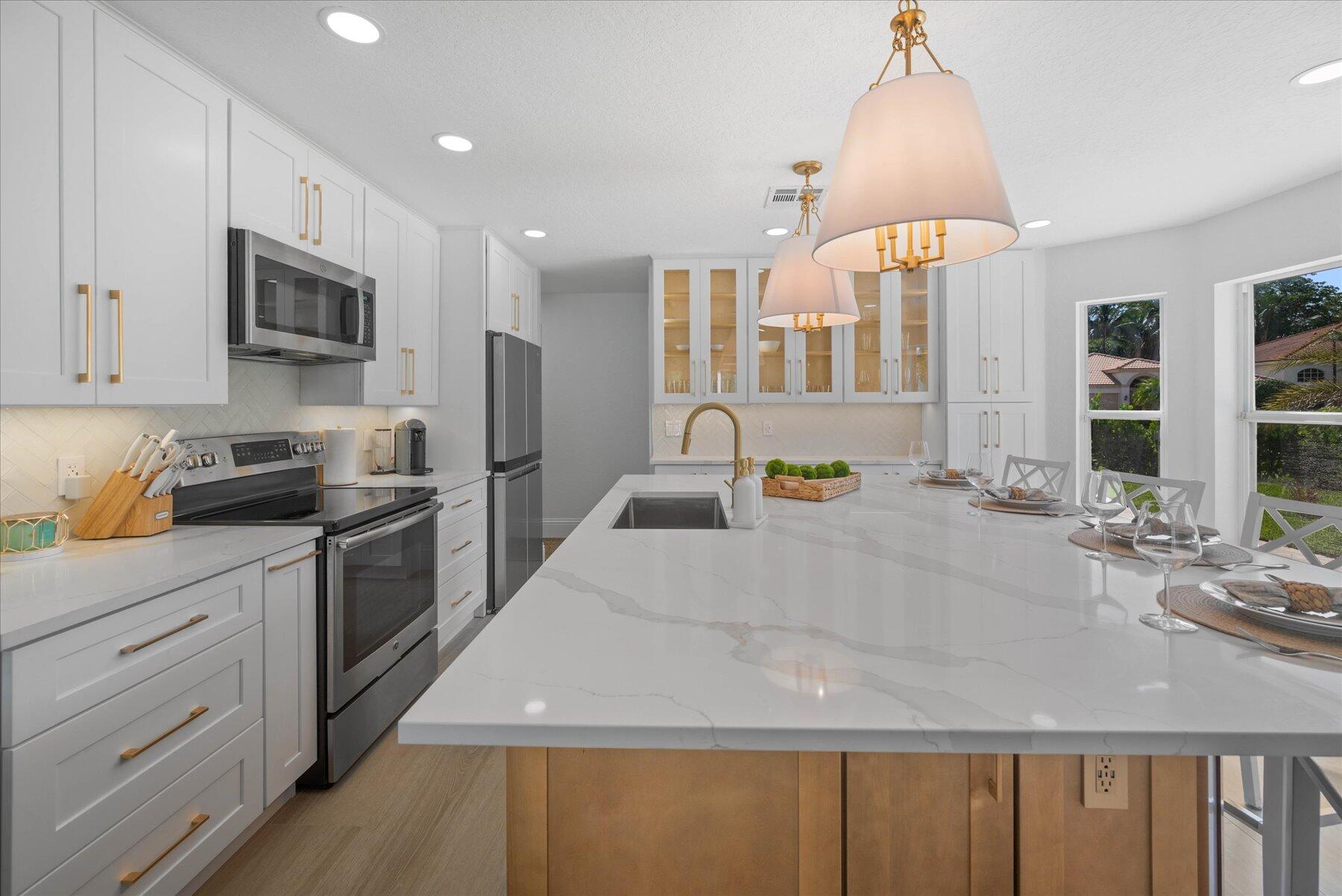 4185 Sea Mist Way Wellington, FL 33449 - Photo 12 of 50 a large kitchen with kitchen island granite countertop a sink a counter space and stainless steel appliances