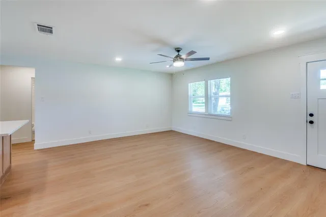 an empty room with windows and ceiling fan